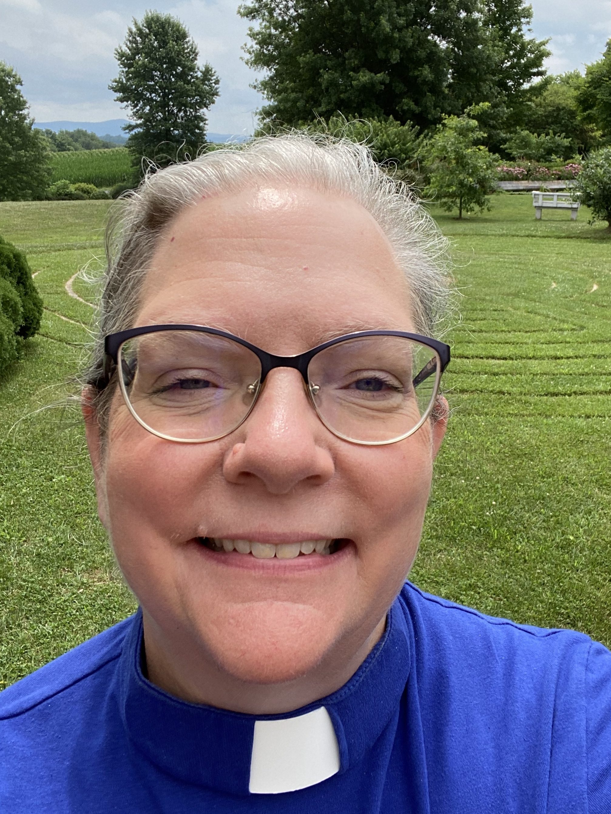 Headshot of Lora standing in front of a labyrinth in a field.